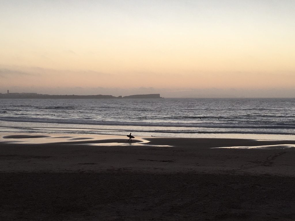 Surfers on the beach at sunset